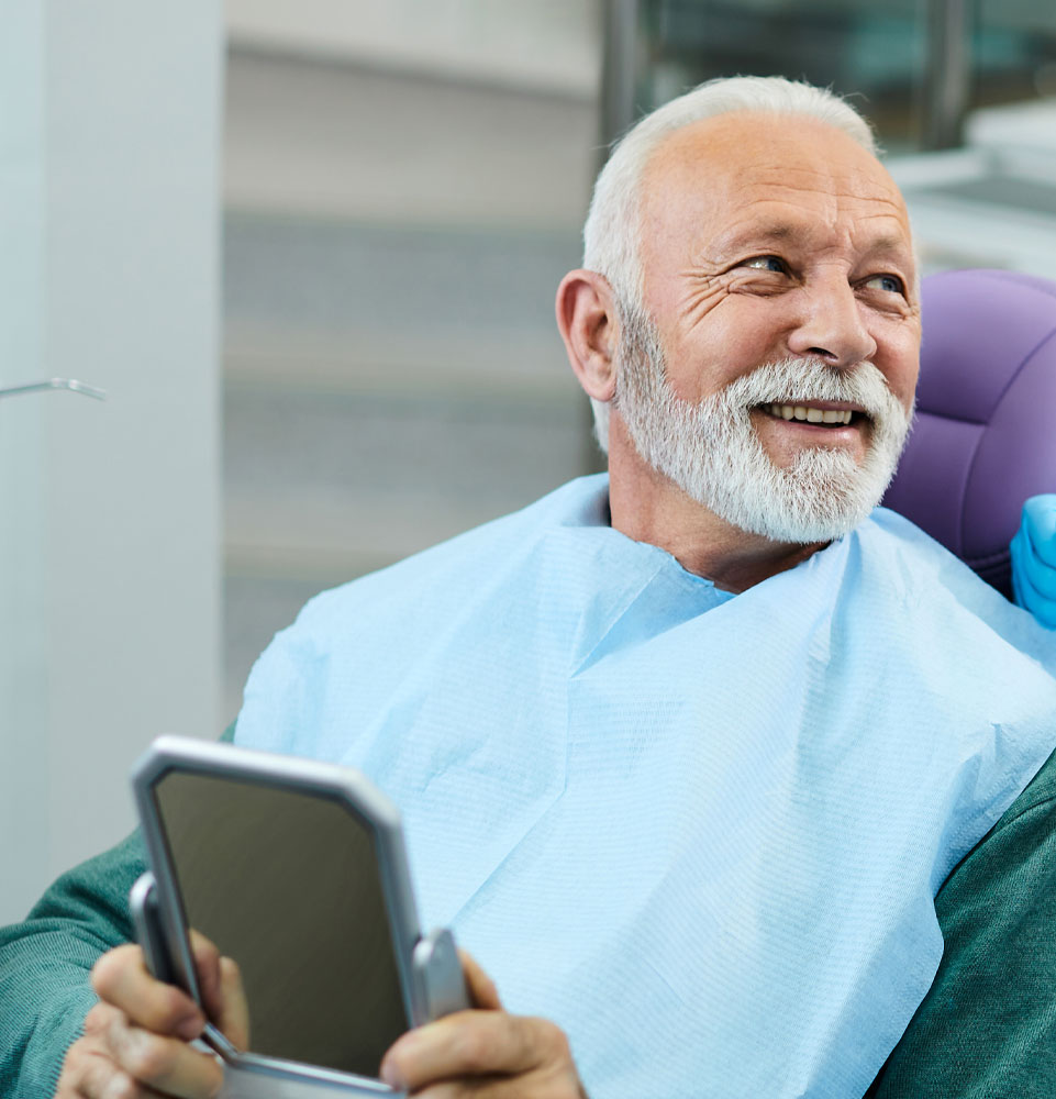 older man with new smile happy looking in a mirror